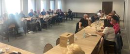 ludzie siedzący przy stołach ustawionych w kształcie litery U na nowoczesnej sali konferencyjnej