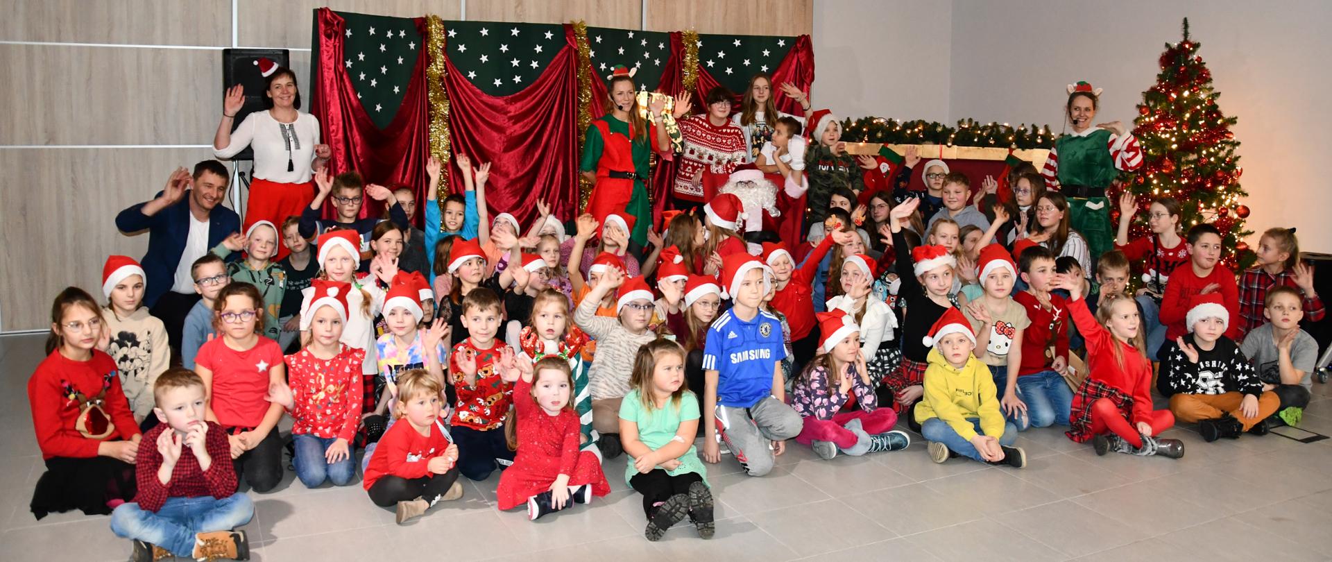 Dzieci pozują do zdjęcia grupowego wraz z prowadzącymi w kąciku Mikołaja.