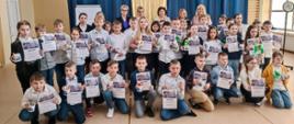 Zdjęcie grupowe laureatów i organizatorów, na którym widzimy wszystkie dzieci wyróżnione w konkursie. Wraz z dziećmi do zdjęcia pozują przedstawiciele władz Powiatu i Miasta oraz organizatorzy w tle niebiesko - złote kotary.