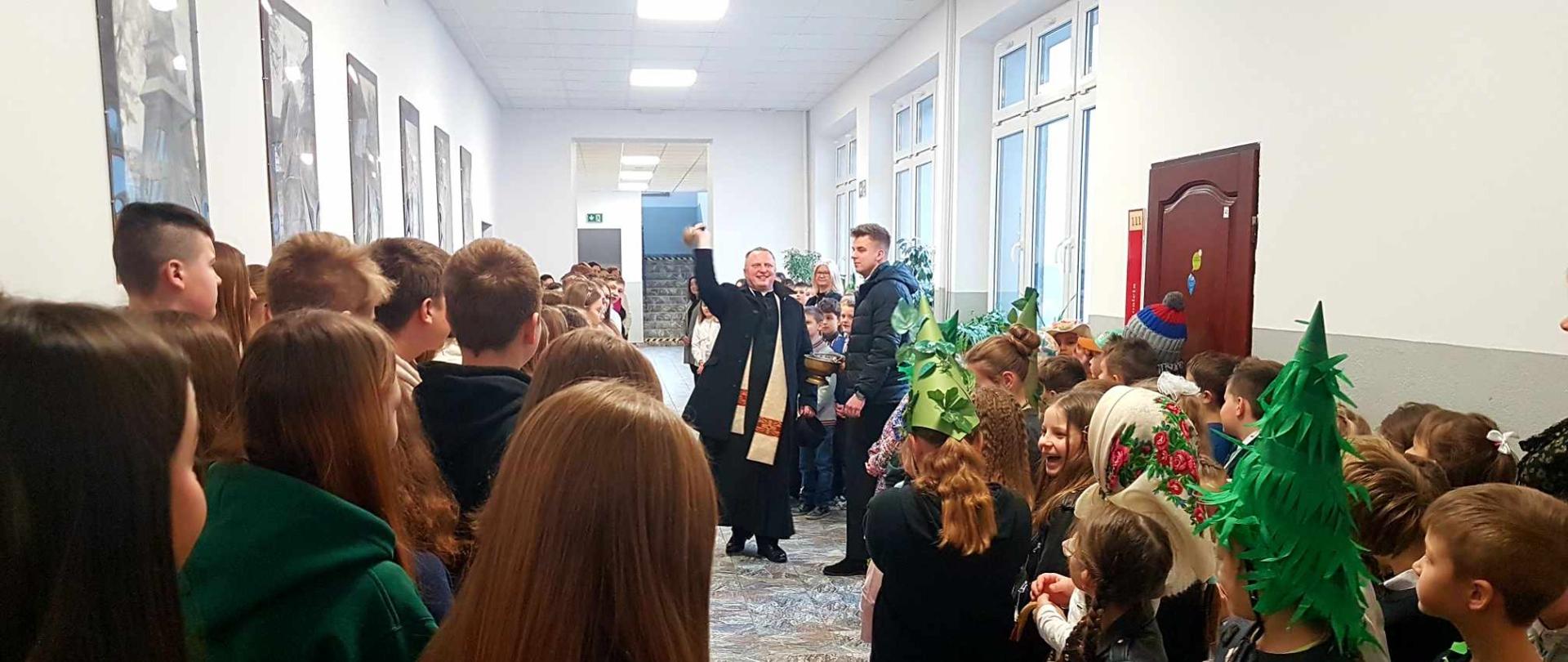 Na korytarzu szkolnym ksiądz proboszcz wraz z wikarym odwiedzają naszą placówkę z wizytą kolędową 
