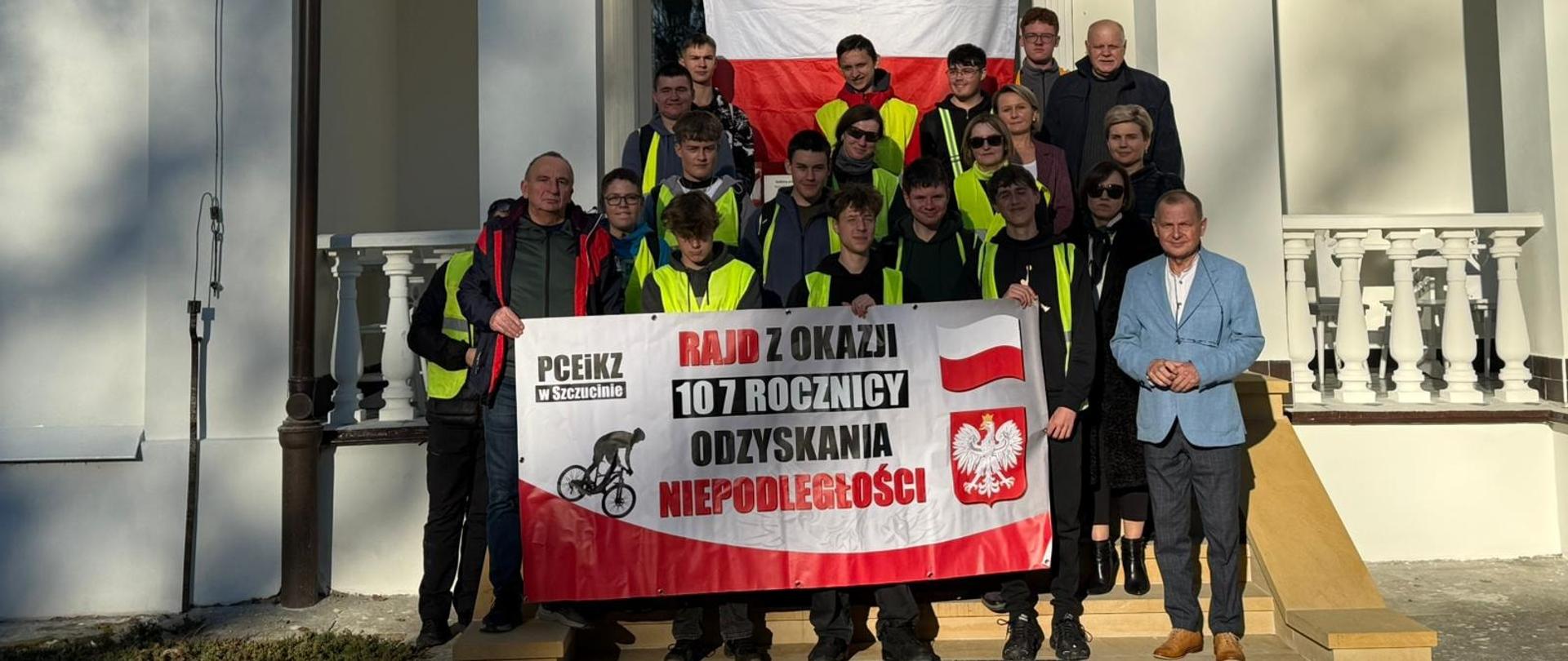 Starosta Dąbrowski i Wicestarosta wraz z dyrekcją, nauczycielami oraz uczniami PCEiKZ w Szczucinie przed dworem Konopków w Brniu, siedzibą Centrum Polonii – Ośrodka Kultury, Turystyki i Rekreacji. Uczestnicy prezentują biało-czerwoną flagę i baner informujący o Rajdzie Rowerowym z okazji 107. rocznicy Odzyskania Niepodległości.