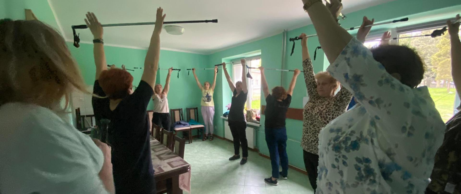 seniorzy ćwiczący z kijkami