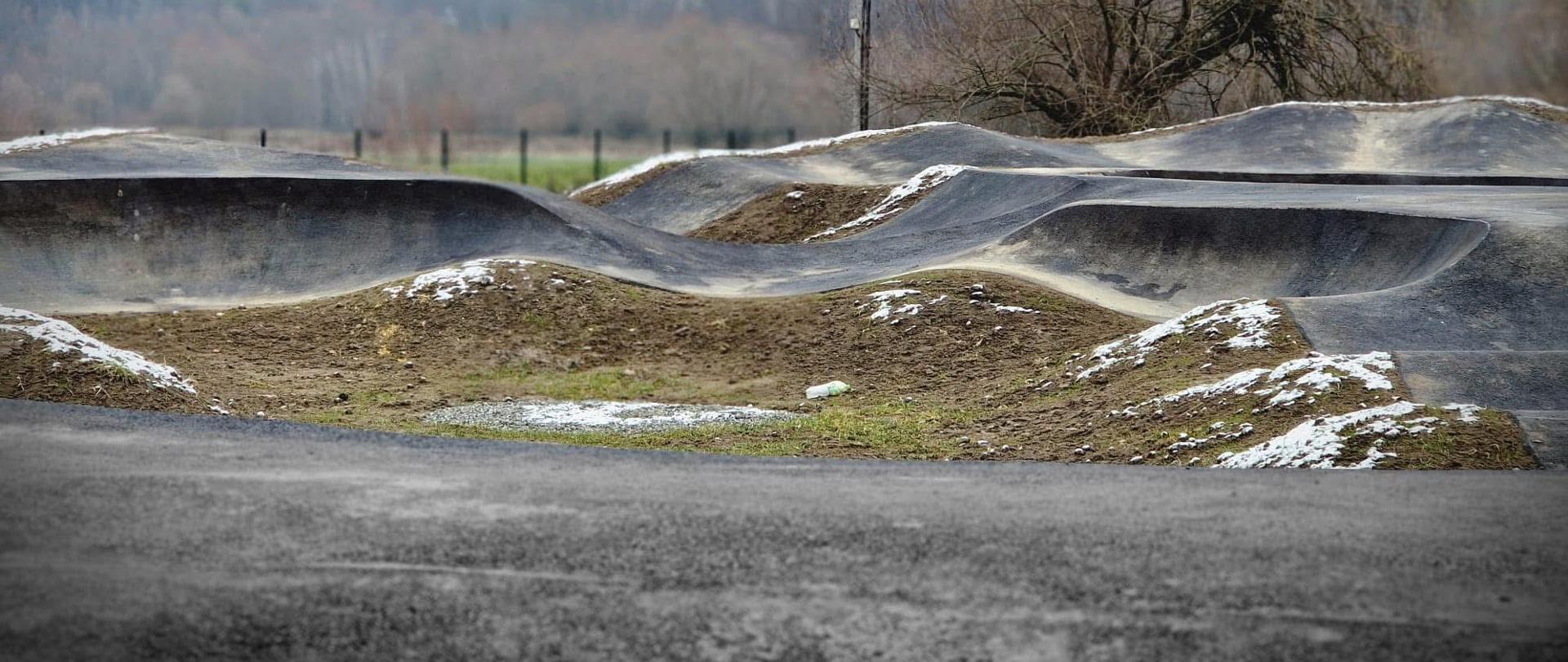 Zdjęcia przedstawiają nowy obiekt, który powstał w Gminie Ciężkowice – jest to sportowy tor pumptrack typu Easy Pump oraz osoby, które uczestniczyły w odbiorze obiektu. 