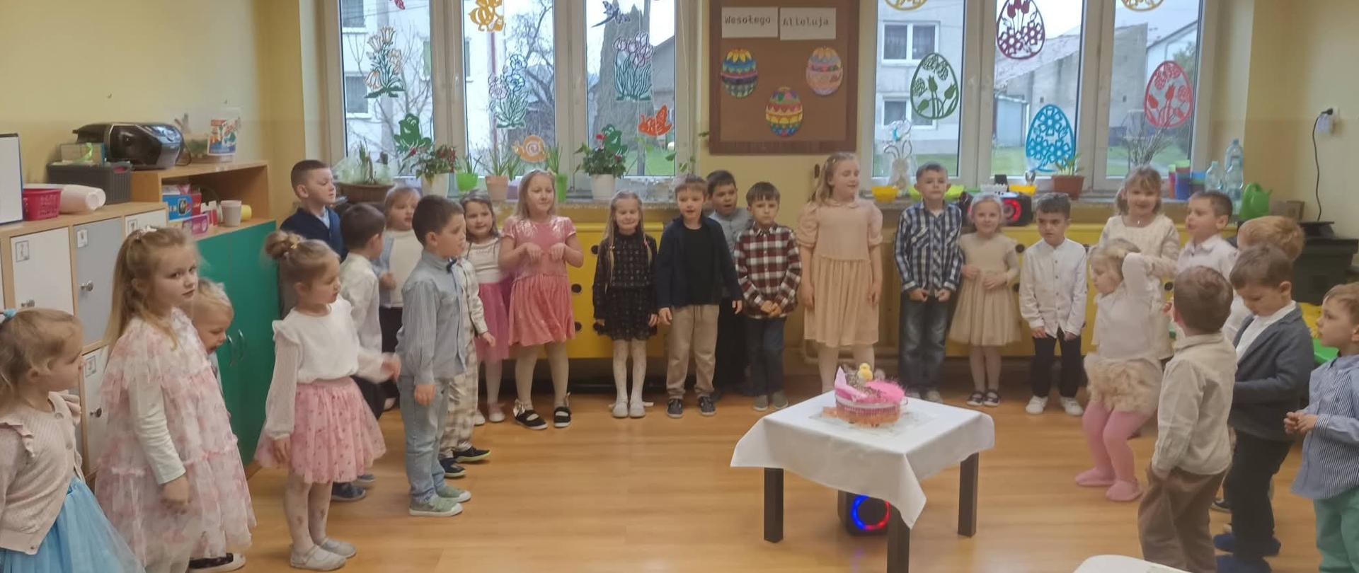Dzieci stoją w półkolu i śpiewają piosenkę w tematyce Wielkanocnej