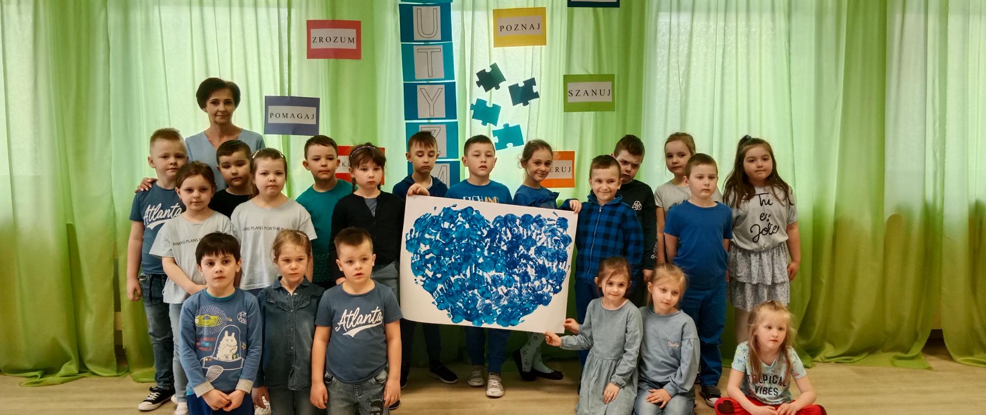 Dzieci z białym kartonem na którym widnieje niebieskie serce 