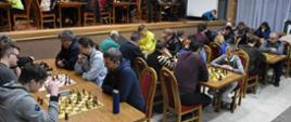 Na zdjęciu szachiści siedzący przy stolikach w trakcie turnieju
