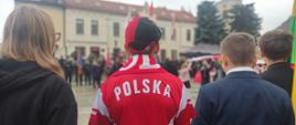 Chłopiec w koszulce z napisem "Polska" na tle urzędu