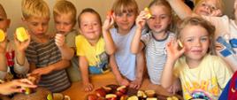 Grupa dzieci podczas zajęć edukacyjnych z okazji Międzynarodowego Dnia Jabłka robi sok