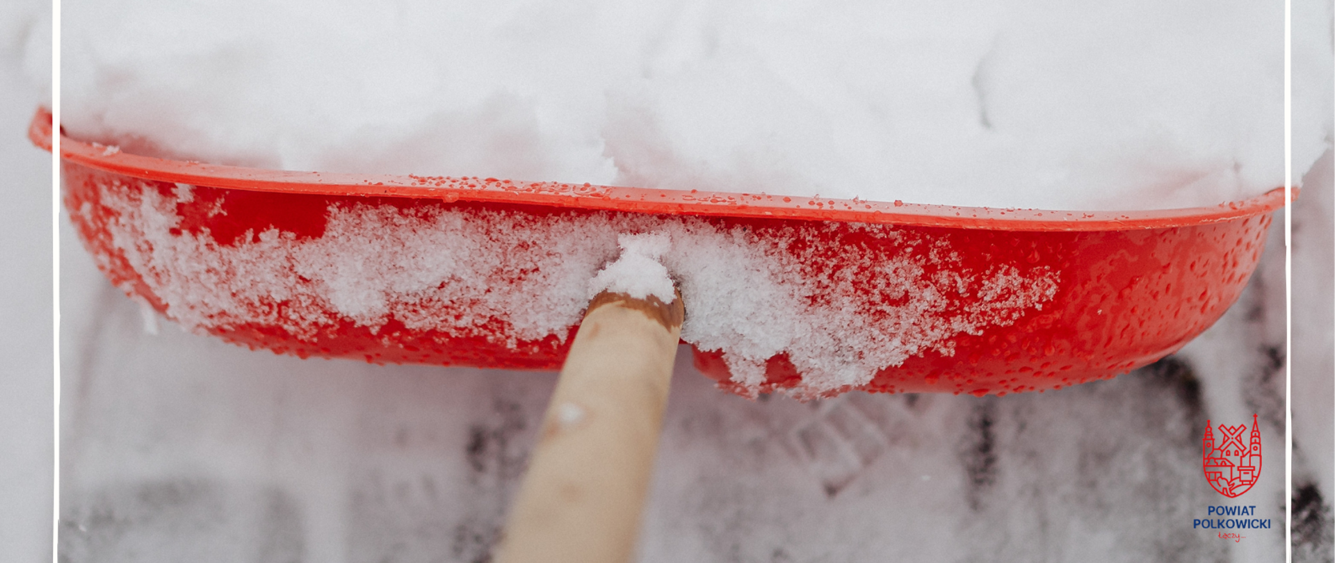 Czerwona łopata do odśnieżania zgarnia śnieg 