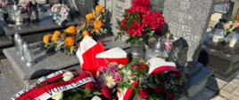 Grób wojenny harcerza Zdzisława Ołtuszewskiego na cmentarzu w Kobiórze, udekorowany kwiatami i zniczami. Przed nagrobkiem złożono wieńce w biało-czerwonych barwach.