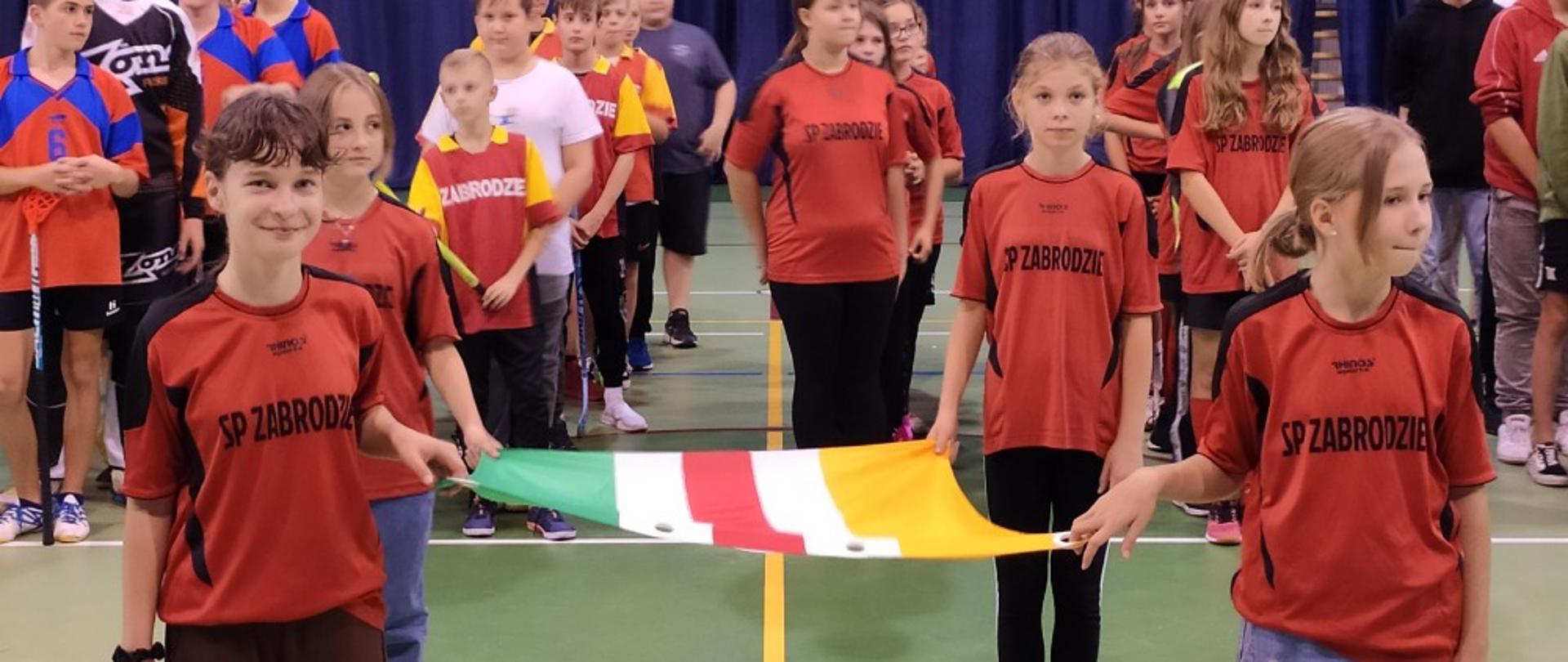 Dzieci trzymają flagę powiatu wyszkowskiego