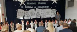 Pani Dyrektor stoi pomiędzy dziećmi przebranymi za bałwanki przemawiając do zebranych gości przed rozpoczęciem uroczystości. Na zdjęciu prezentuje się cała grupa Fajniaków. 
