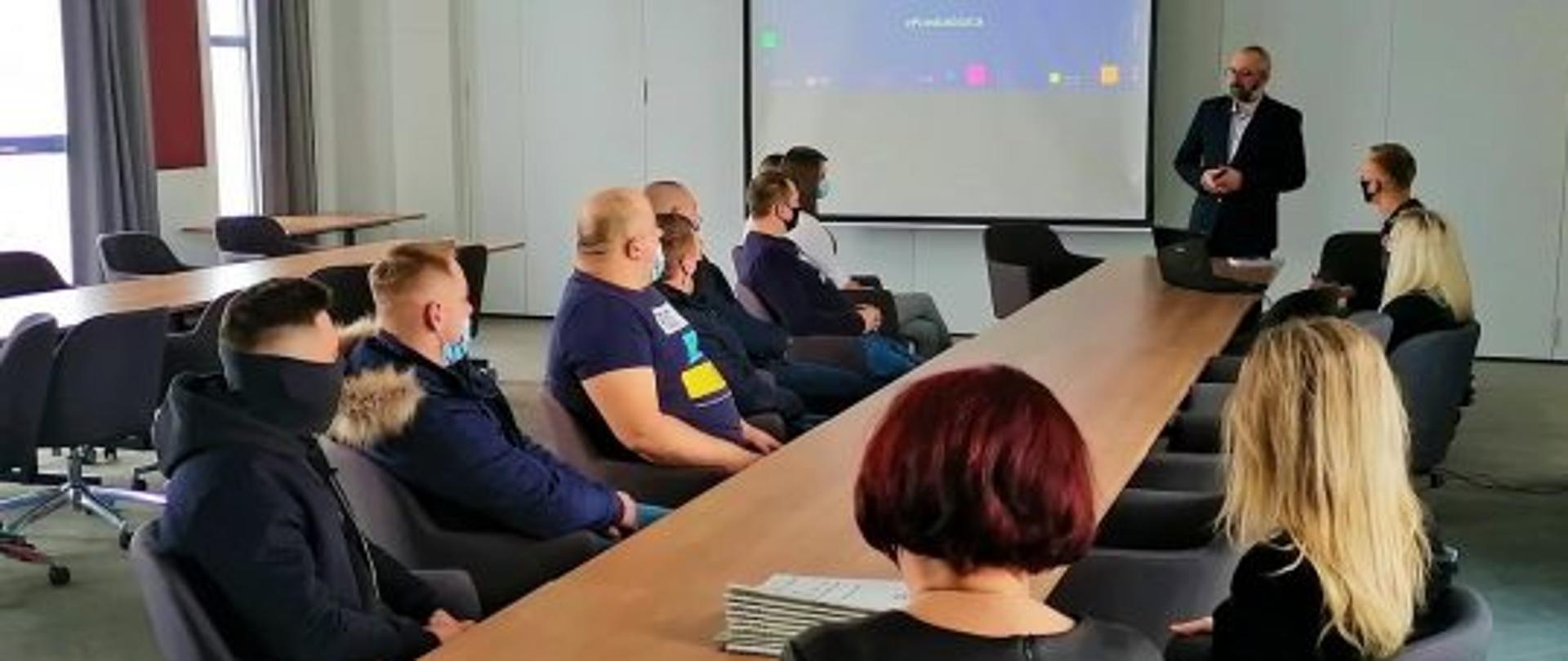 Starosta Powiatu Przasnyskiego Krzysztof Bieńkowski przemawia do nowych przedsiębiorców, którzy podpisali umowy na dofinansowanie rozpoczęcia działalności gospodarczych. Sala konferencyjna w Centrum Aktywizacji Biznesu Starostwa Powiatowego w Przasnyszu.