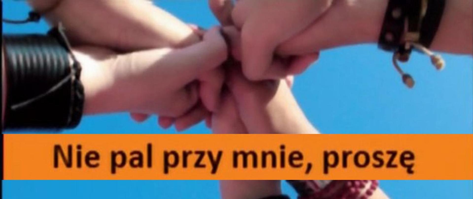Napis na pomarańczowym tle, w tle trzymające się ręce.