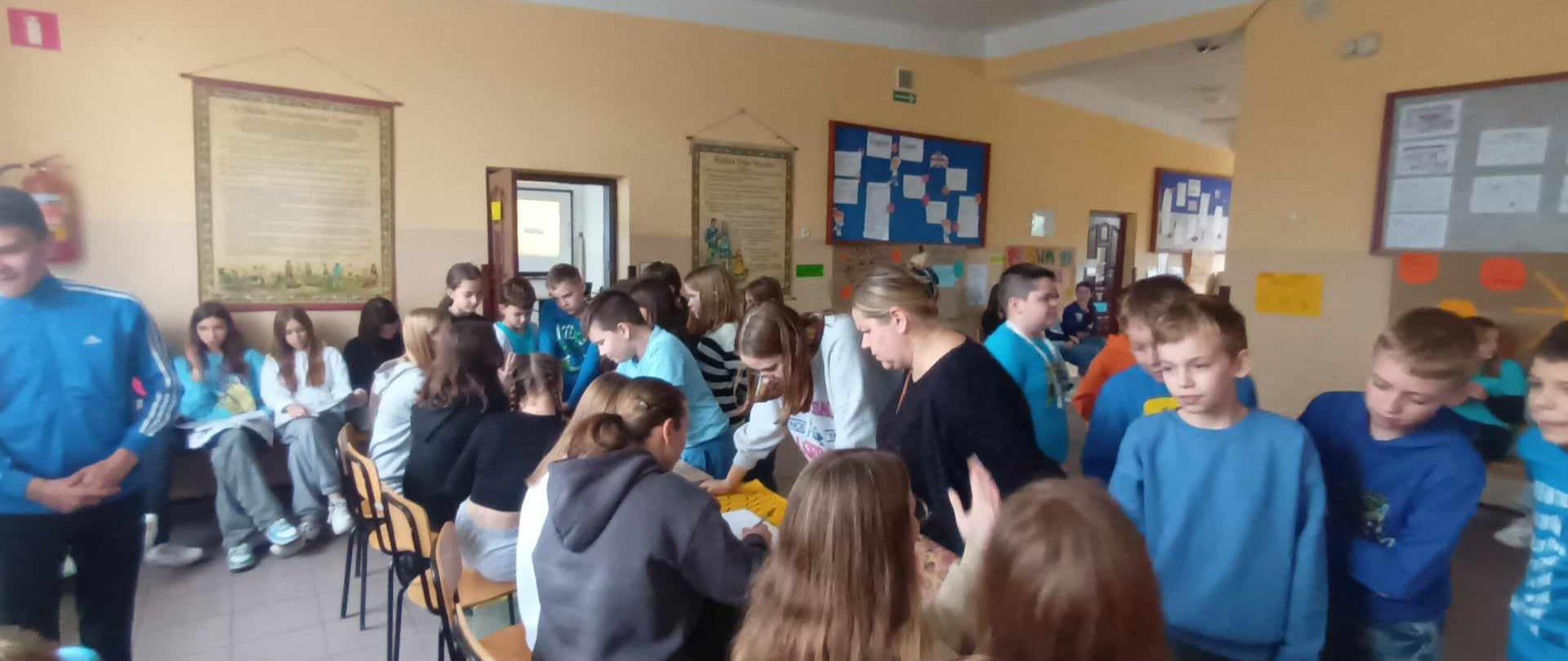 Uczniowie klasy 4 uczą się mnożyć na palcach przy stolikach edukacyjnych prowadzonych przez uczennice klasy 8a.