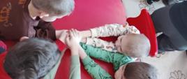 Gry edukacyjne - dzieci siedzą przy stole, trzymają się za ręce