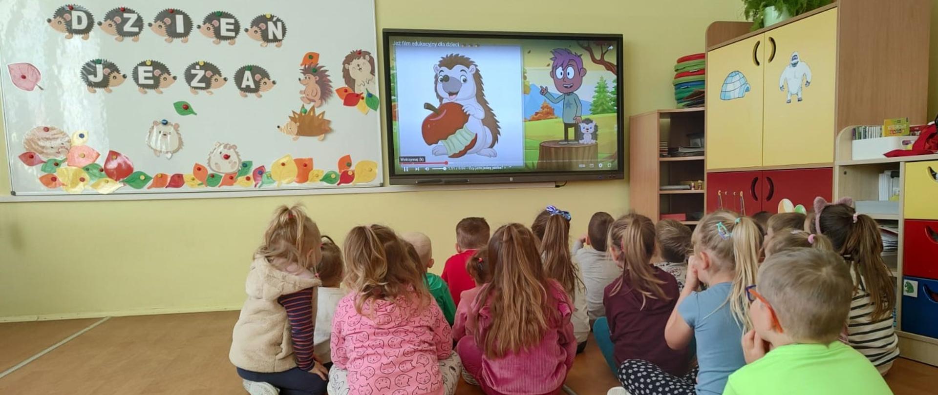 Dzieci oglądają film edukacyjny o jeżu.