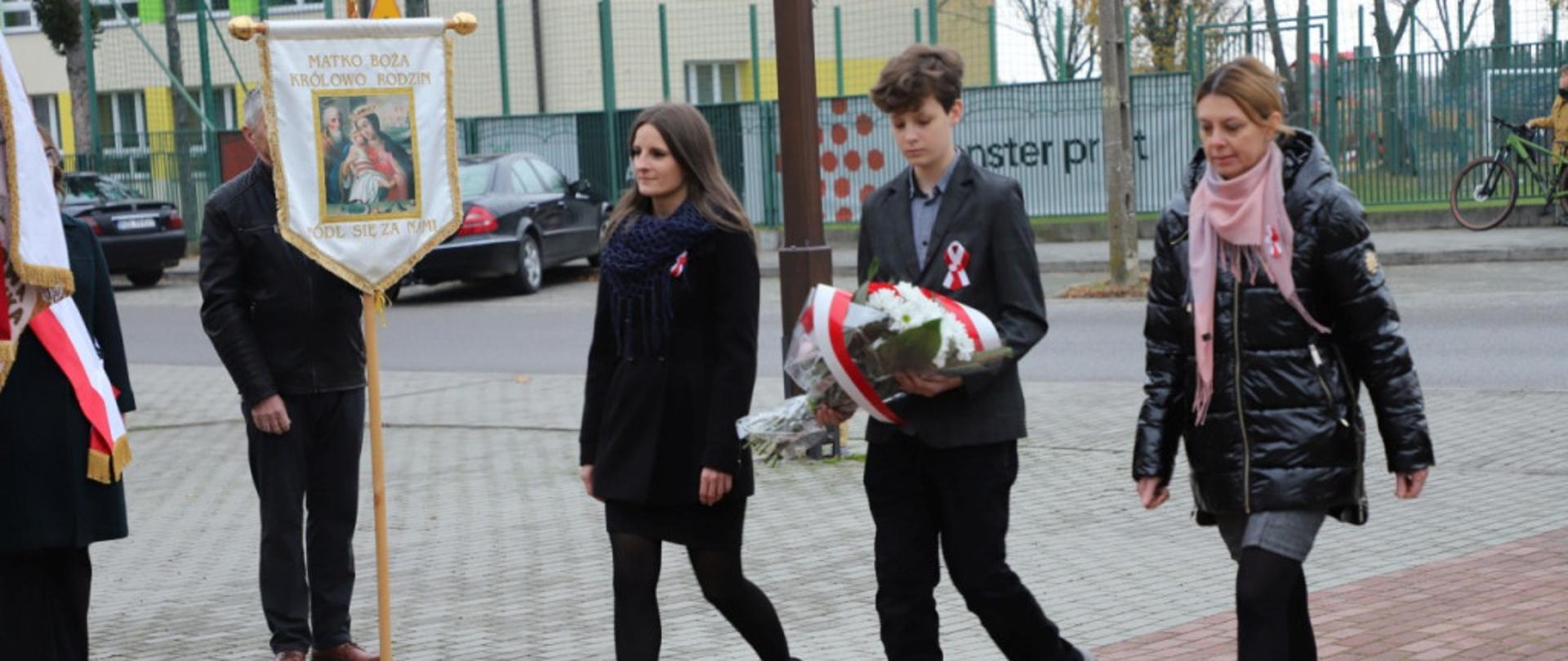 Delegacja dyrektor Barbara Durej, wicedyrektor Alicja Siebierańska i uczeń składają wiązankę na miejscu pamięci
