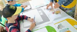 uczymy się zasad segregacji śmieci - przy stole z planszami siedzą dzieci