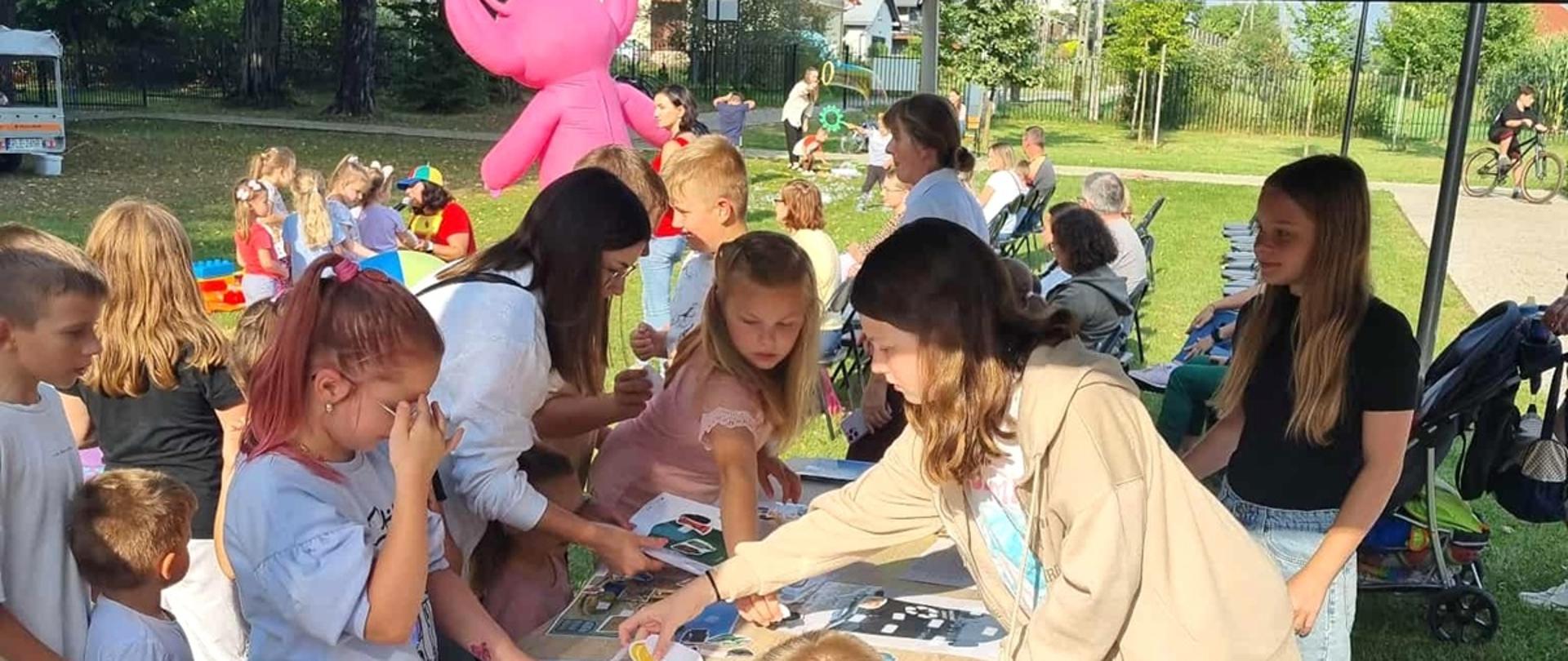 dzieci w wieku szkolnym stoją wokół stołu i wykonują zadania plastyczne, piękna słoneczna pogoda 