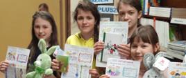 Uczniowie trzymają w ręku nagrody czyli maskotki lub kubki w kształcie zwierząt oraz ozdobione kartki lekturownika, na których opisali przeczytaną książkę
