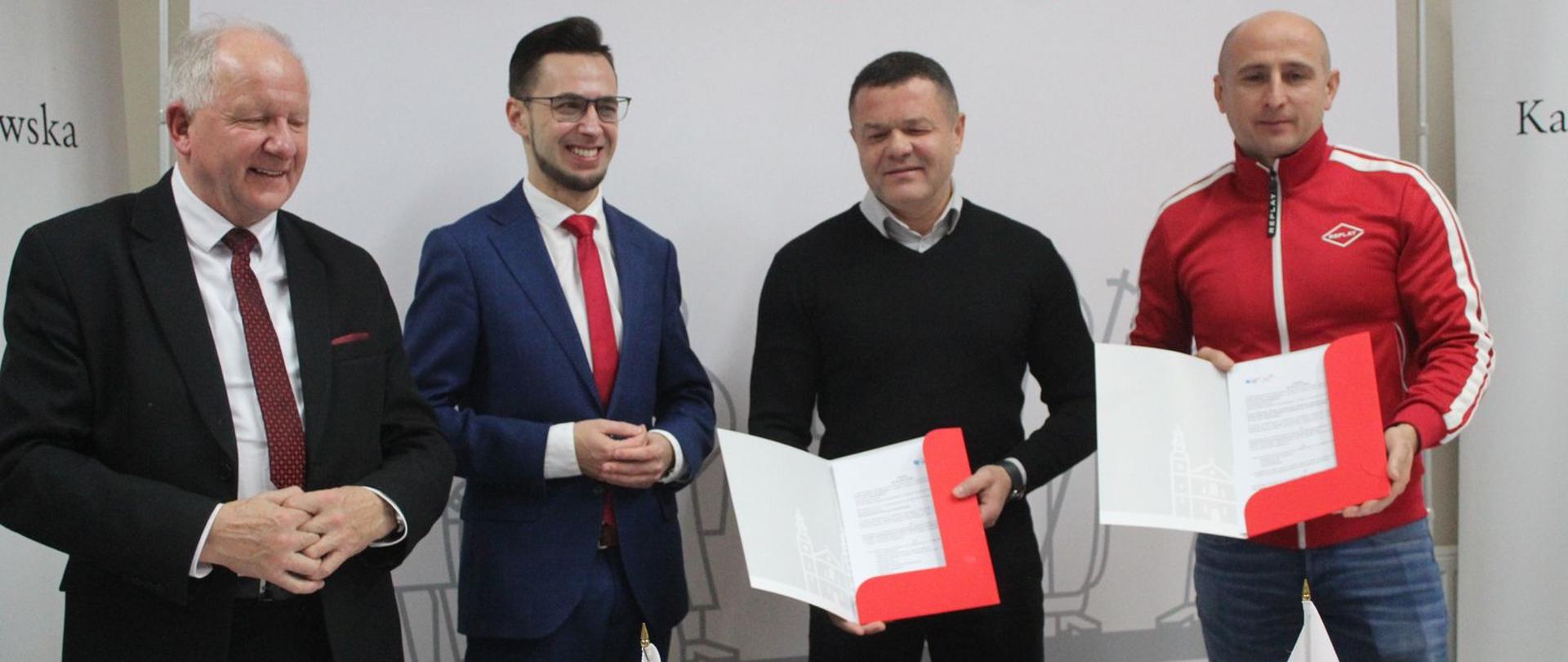 Fotografia przedstawia podpisanie umów, 4 osoby w pozycji stojącej. Od lewej Burmistrz Miasta Augustyn Ormanty, Poseł RP Filip Kaczyński. 