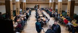 Widok z sali - przy stołach siedzą uczestnicy, rozgrywają partię szachów