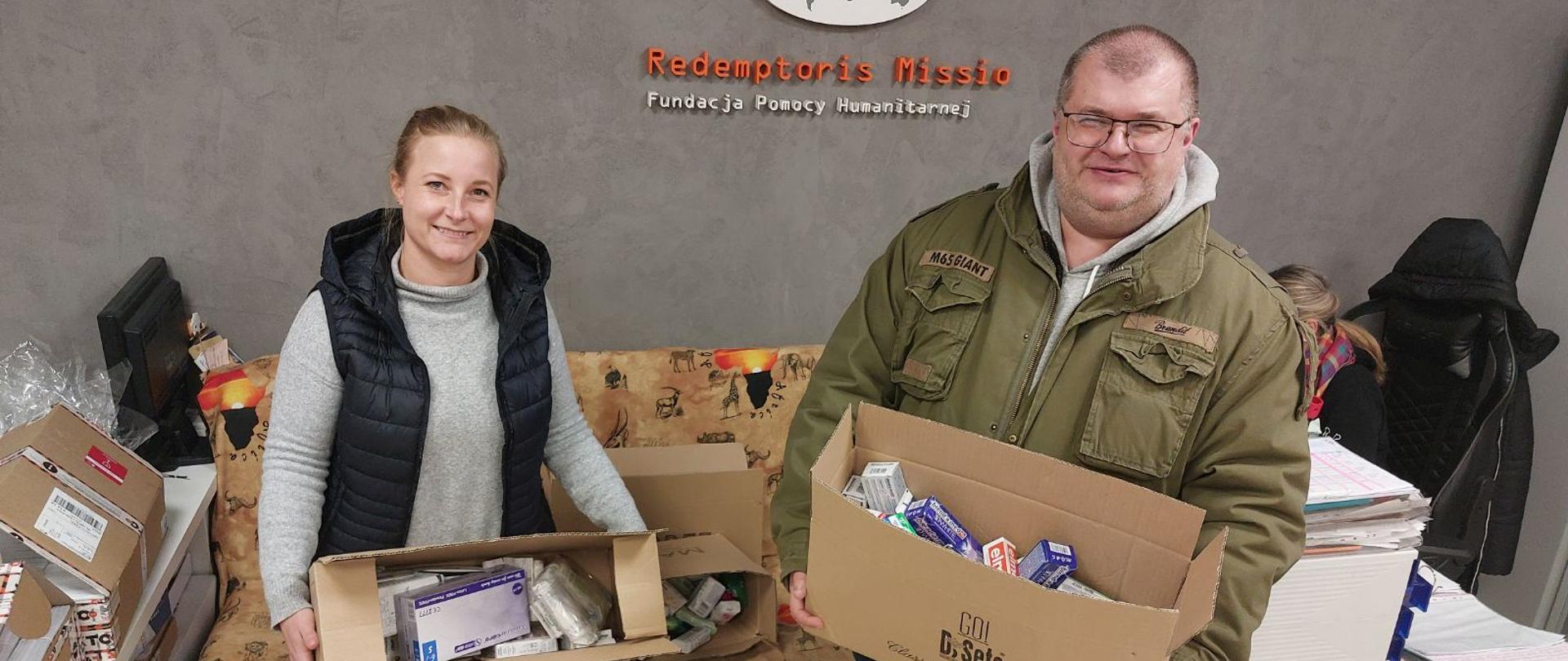 Mężczyzna i kobieta trzymają po kartonie w rękach. W środku są pudełka z pastą do zębów, szczoteczkami i mydłem