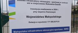 Tablica informacyjna o inwestycji "Budowa infrastruktury rekreacyjno-sportowej w centrum wsi w miejscowości Bukowina- Osiedle. Dotacja w wysokości 171 585,00 zł. 