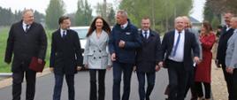 Przedstawiciele lokalnych władz i służb państwowych, idący nowo wybudowaną drogą.