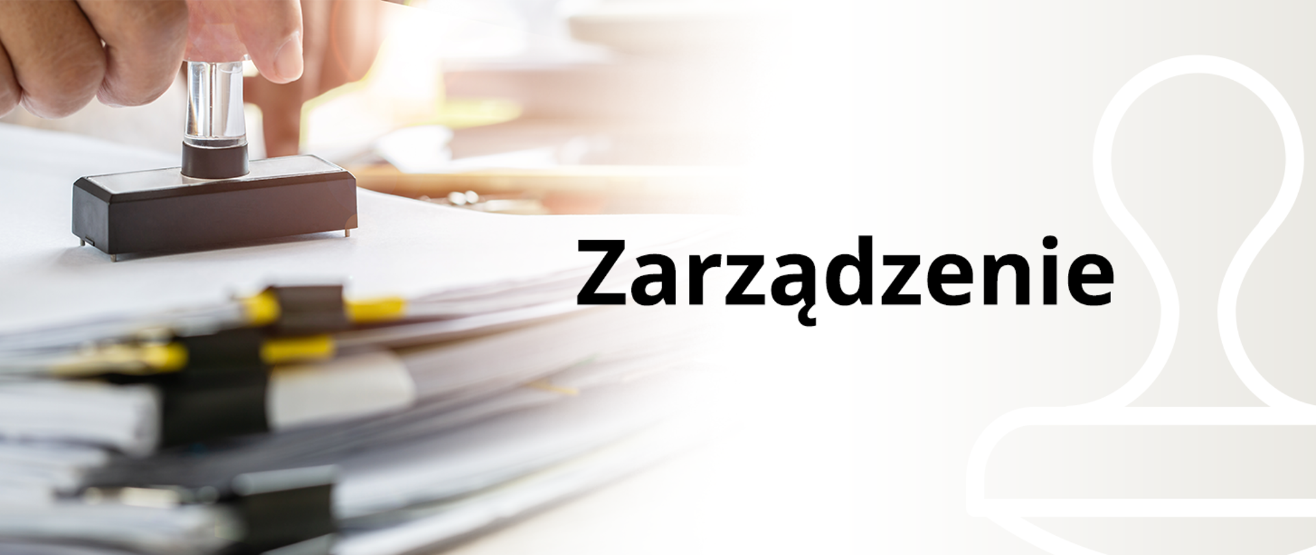 Na zdjęciu widać rękę osoby stemplującej dokument za pomocą prostokątnego stempla. Na pierwszym planie z lewej strony widać stos dokumentów spiętych spinaczami, po prawej stronie obrazu wyraźnie widoczne jest słowo “Zarządzanie”.