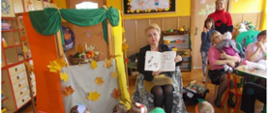 Dyrektor przedszkola prezentuje fragment książki w otoczeniu dzieci