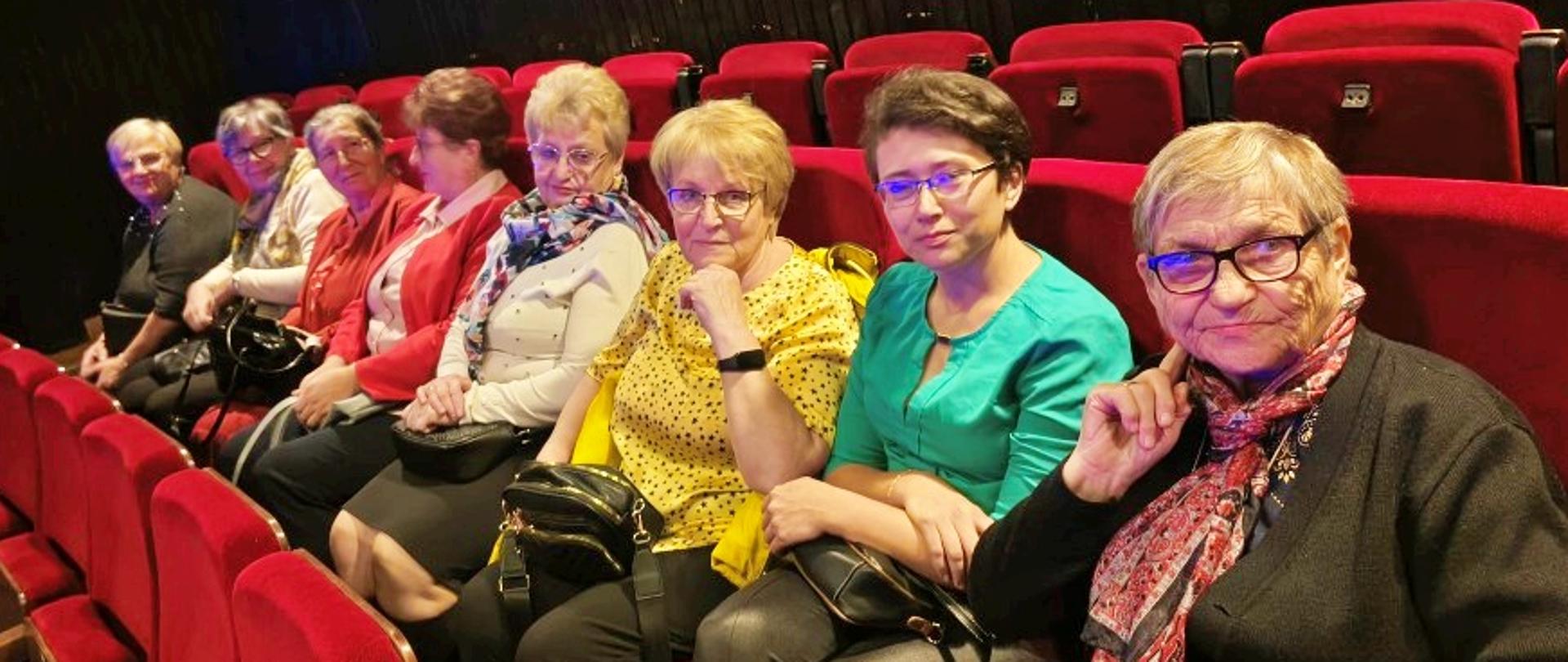 seniorzy siedzą na sali widowiskowej