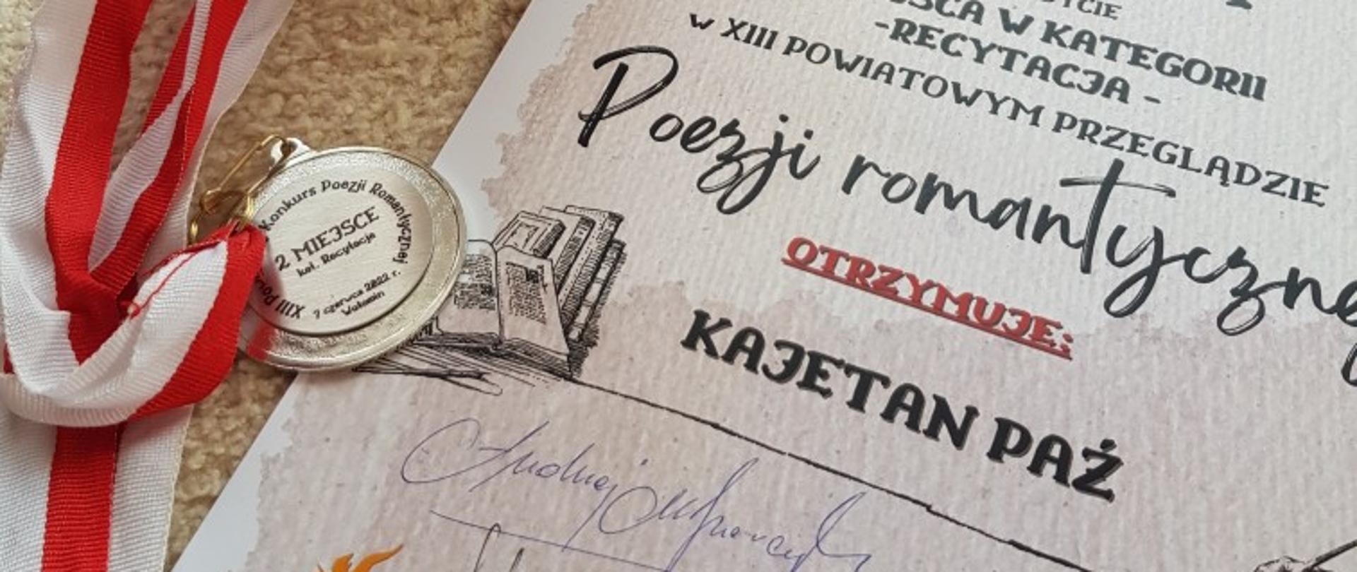 Dyplom dla Kajetana Paź. Obok medal na biało czerwonej wstążce