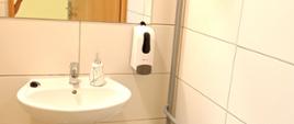 Wnętrze wyremontowanej łazienki z umywalką, lustrem nad nią, pojemnikiem na mydło i koszem