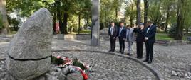 Reprezentanci Powiatu Sokołowskiego stoją przed pomnikiem z pochylonymi głowami po złożeniu kwiatów.
