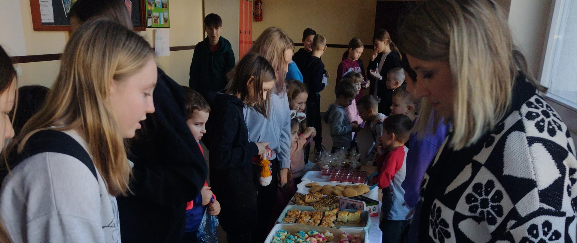 Stoisko ze słodkościami zerówki i chętni uczniowie do zakupu.