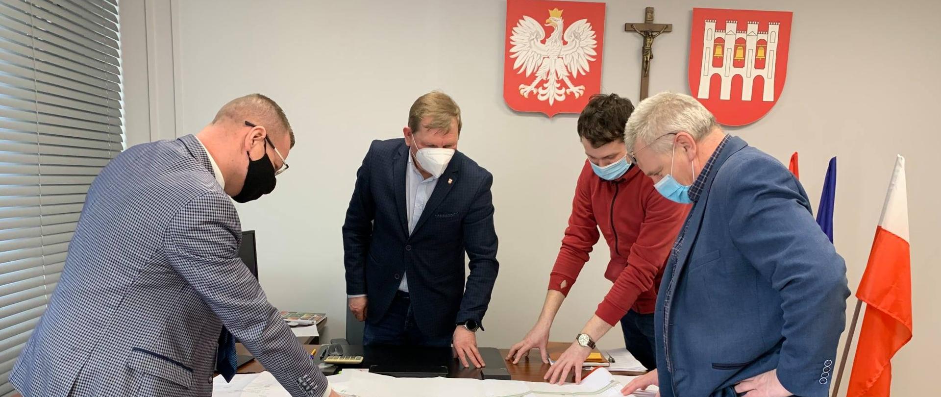 na obrazku w budynku Urzędu Gmina Rutkiod lewej strony stoją: Wicestarosta Zambrowski, Wójt Gminy Rutki, pracownik wydziału IR oraz Naczelnik Wydziału IR w tle widać na ścianie godło, krzyż oraz logo gminy