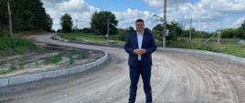 Poseł Marcin Porzucek stoi na remontowanej drodze.