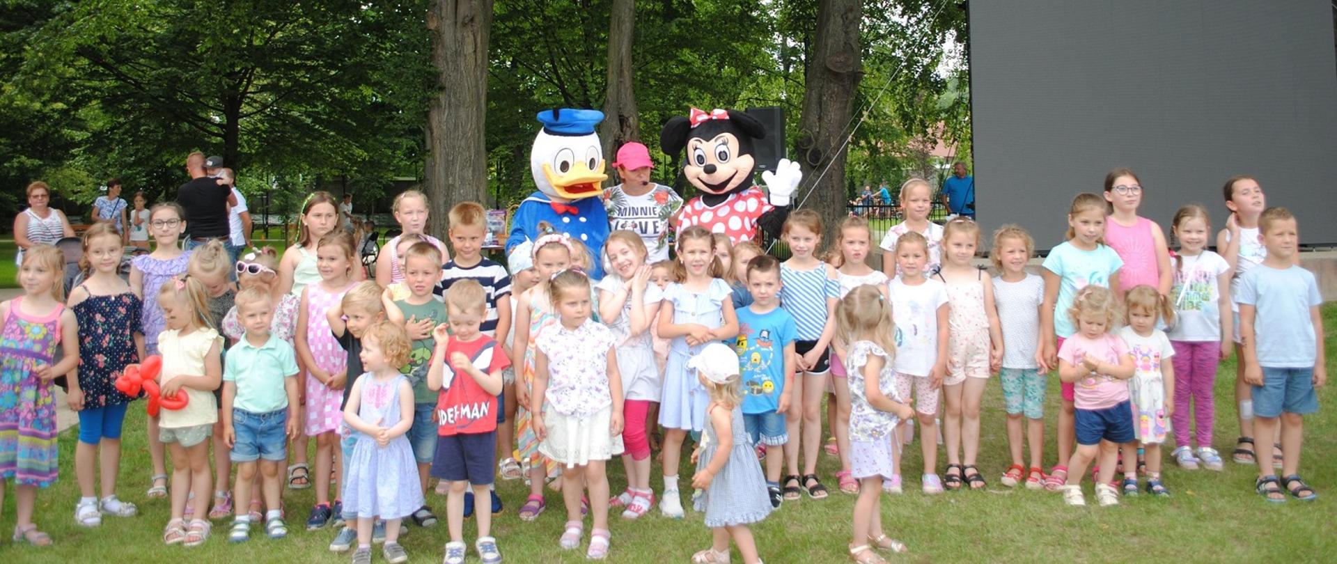 dzieci w letnich ubraniach pozują do zdjęcia z myszka mini i kaczorem Donaldem 