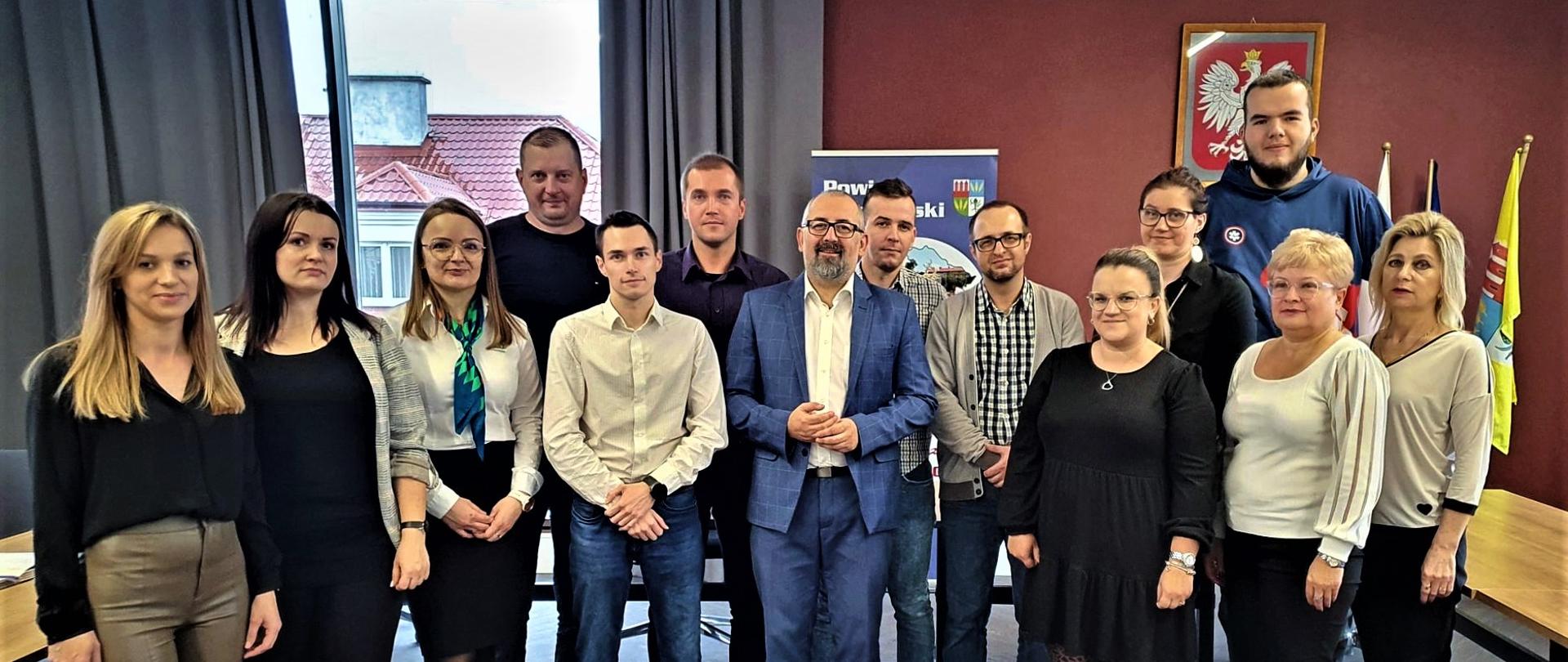 Zdjęcie przedstawia przedsiębiorców, którzy otworzyli swoje działalności przy pomocy Powiatowego Urzędu Pracy w Przasnyszu, przedstawicieli Urzędu Pracy oraz Starostę Przasnyskiego Krzysztofa Bieńkowskiego. Fotografię wykonano w sali konferencyjnej Centrum Aktywizacji Biznesu w siedzibie Starostwa Powiatowego w Przasnyszu.