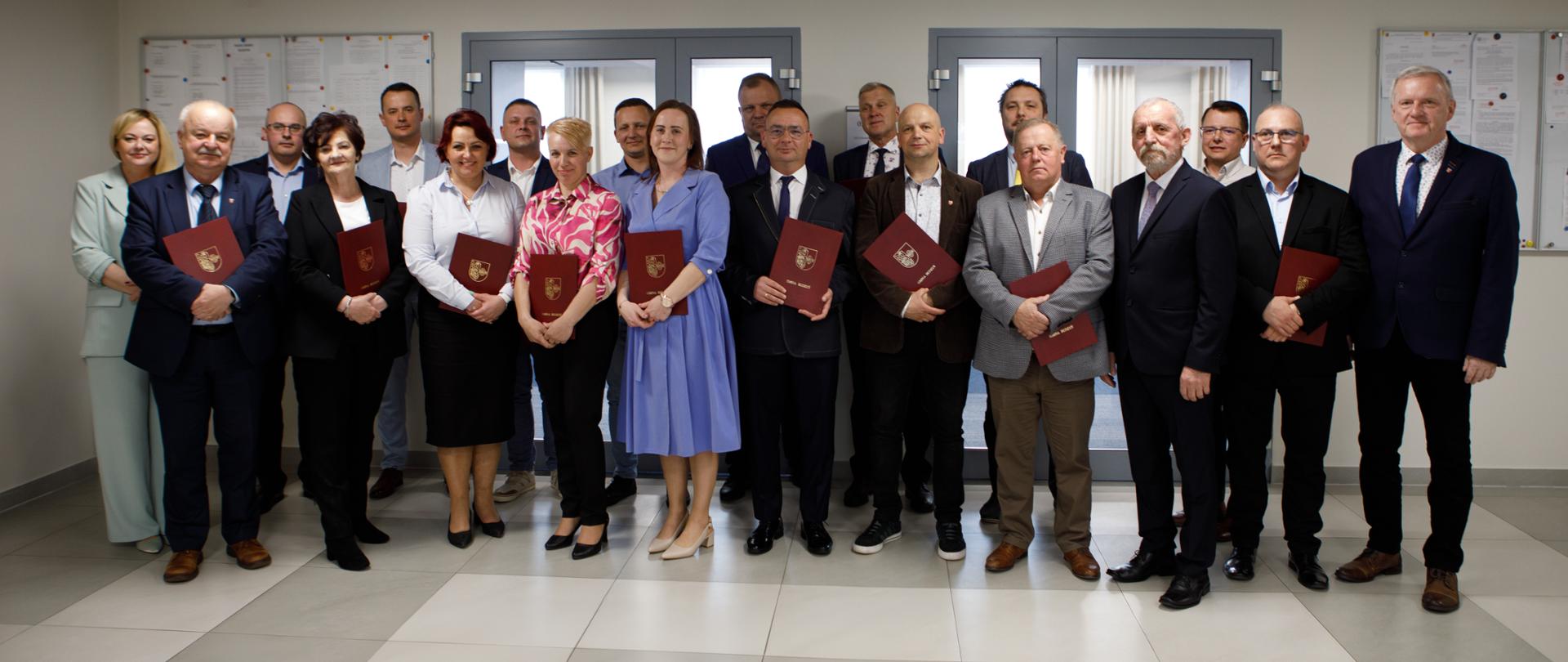 Radni Rady Miejskiej w Budzyniu stoją obok siebie trzymając zaświadczenia