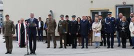 Zaproszeni goście stoją za prowadzącym wydarzenie