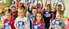 Na zdjęciu dzieci trzymające w rękach aktywizującą książeczkę otrzymaną w ramach realizacji programu "Czyściochowa Akademia"