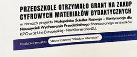 Plakat przedstawiający dwoje dzieci i nauczycielkę bawiące się robotami, poniżej napis "Przedszkole otrzymało grant na zakup cyfrowych materiałów dydaktycznych w ramach projektu Małopolska Ścieżka Rozwoju"