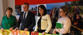 3 kobiety i mężczyzna stoją trzymając przed sobą kolorowe karty