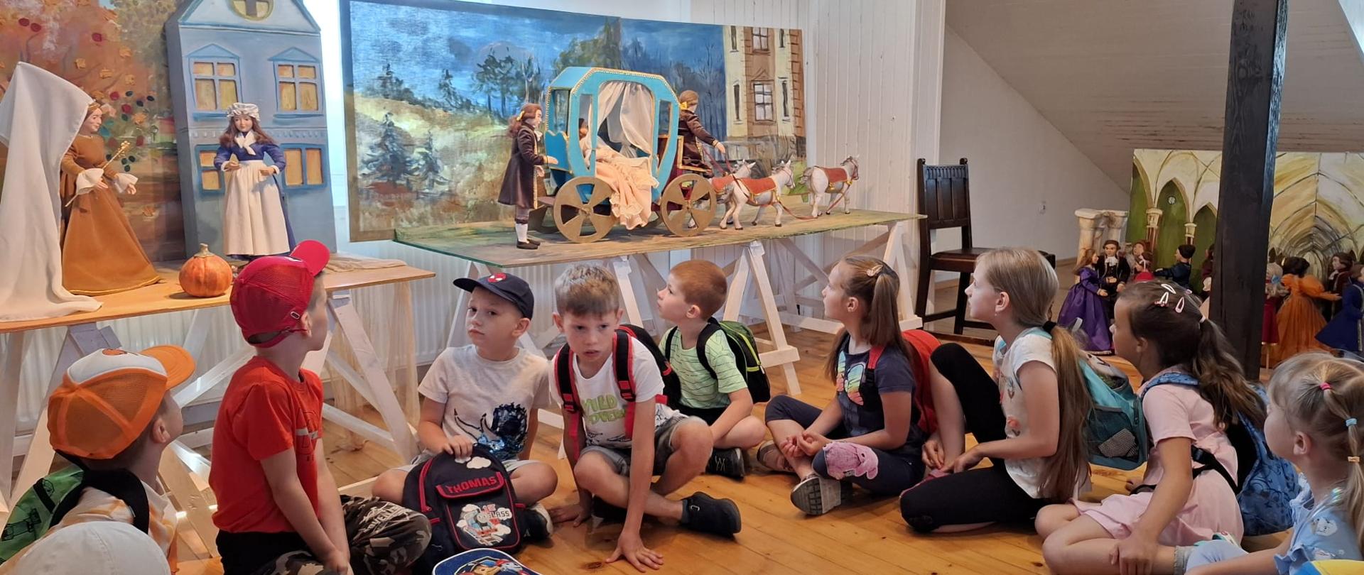 Zdjęcie grupowe dzieci, a w tle lalki z różnych baśni.