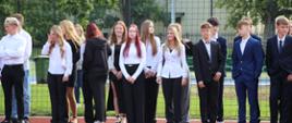 Uczniowie w odświętnych strojach na boisku szkolnym
