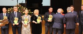 Moment wręczenia pamiątkowych statuetek - nagrodzeni pozują do zdjęcia