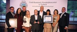 Grupa ludzi pozuje do zdjęcia pod banerem Cech